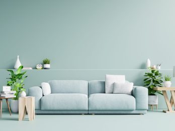Modern living room interior with sofa and green plants,lamp,table on light green wall background. 3d rendering